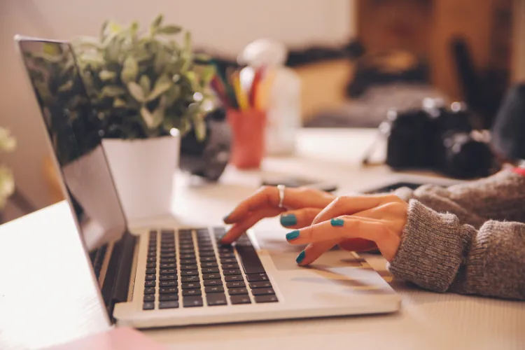 girl with blue nails typing on laptop